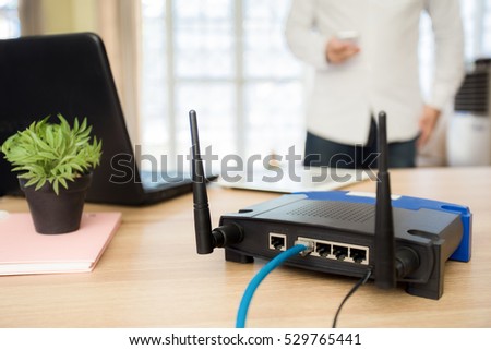 closeup of a wireless router and a man using smartphone on living room at home ofiice