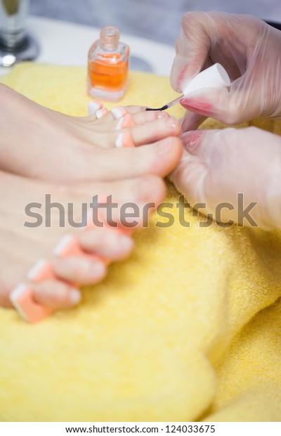Close-up of woman applying nail varnish to toe\
nails at spa center