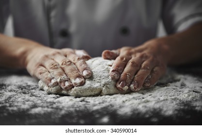 Close-up of woman baker hands kneading the dough on black board with flour powder. Concept of baking and patisserie.   