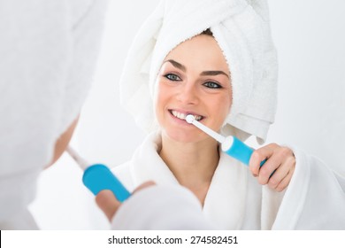Close-up Of A Woman In Bathrobe Brushing Teeth