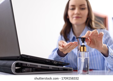 closeup woman in blue shirt cleans hands with sanitizer while sitting at laptop. remote work concept - Powered by Shutterstock