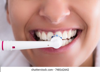 Close-up Of A Woman Brushing Teeth Using Electric Toothbrush
