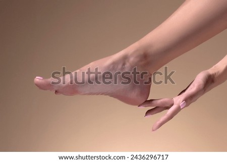 Closeup woman cares about her feet on beige studio background