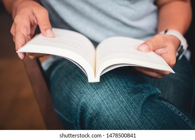 Closeup woman in casual cloths sitting on the chair and rest the book on her lap to read