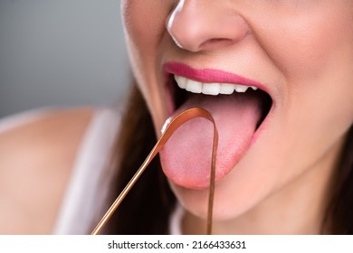 Close-up Of A Woman Cleaning Her Tongue With Cleaner