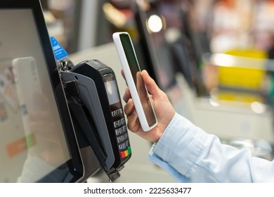 Closeup Woman Counter Buy electronic payment supermarket smartphone Female hand with a mobile phone in pay for purchases in stores Contactless NFC Terminal Closeup card reader.