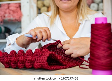 Close-up Of Woman Crocheting Using Crochet Hook And Burgundy Yarn In Art And Craft Workshop