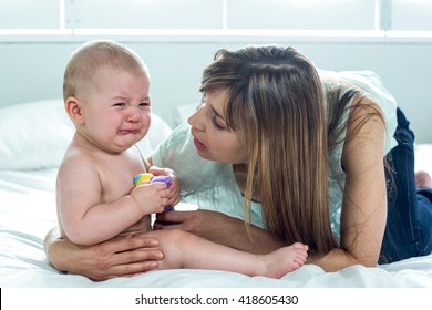 Close-up of woman with crying son on bed at home