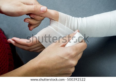Close-up of woman doctor bandaging a hand.