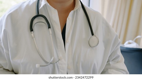 closeup woman doctor wearing white medical coat and stethoscope, doctor prepares to examine the patient in the office, holds a part of the stethoscope in his hand