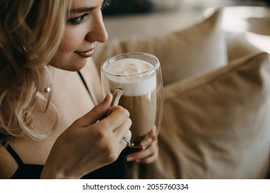 Closeup Of A Woman Drinking Latte From A Double Glass Cup, Sitting On A Sofa.