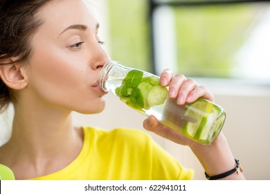 Close-up Of A Woman Drinking Water With Mint, Cucumber And Lime During A Workout With Dumbbells. Detox Dieting Concept