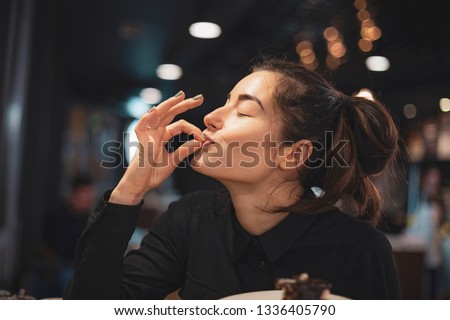 Closeup of woman eating chocolate cake in a cafe. selective focus, noise effect