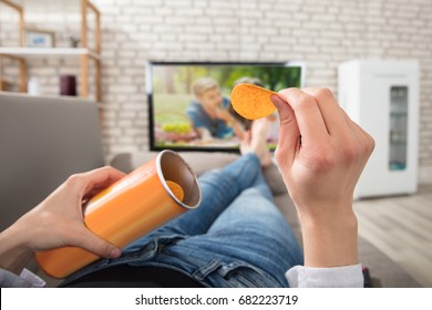 Close-up Of A Woman Eating Potato Chips While Watching Television