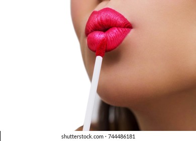 Close-up Of Woman Face With Bright Red Matte Lipstick On Full Lips, girl rouging her lips, holding red lipstick, mouth is gently open. Isolated on background. . Beauty, Cosmetics, Makeup Concept.