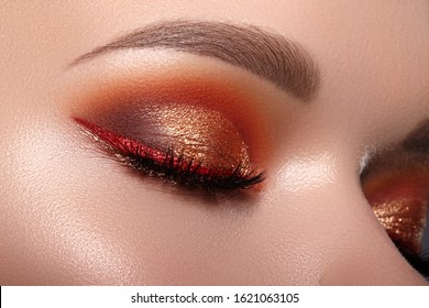 Closeup Of Woman Face With Eyes Make-up. Fashion Celebrate Makeup With Red Liner, Gold Shadows, Glowy Clean Skin, Perfect Shapes Of Brows. Macro Of Female Eye. Halloween Style