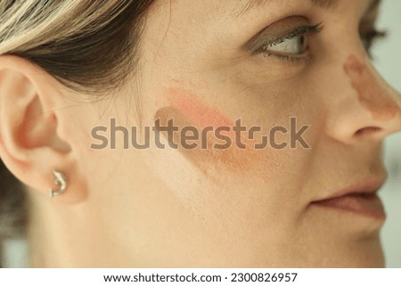 Close-up of woman face with tone cream lines on skin. Makeup, beauty and skin care concept
