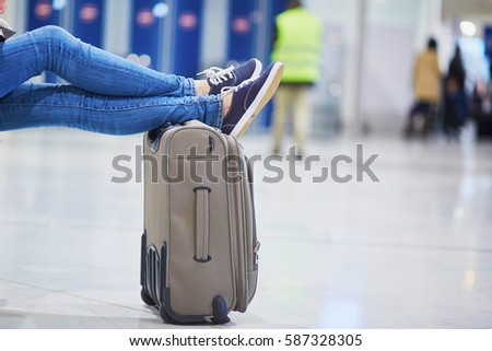 Closeup of woman feet on a suitcase in international airport. Delayed or canceled flight concept