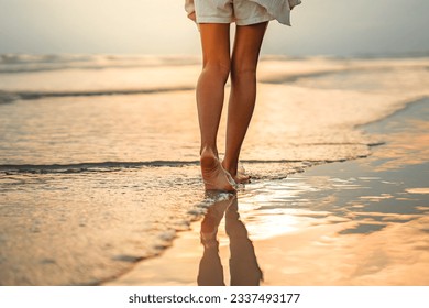 Closeup of woman feet walking on sand beach during a golden hour sunset. Travel and relaxing in summer