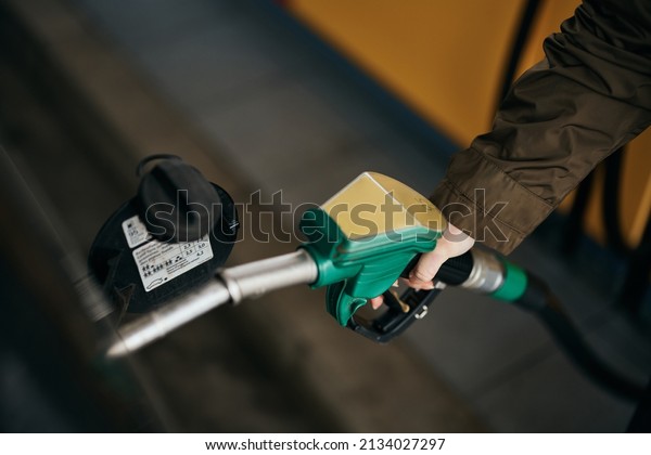 Close-up of\
woman filling car fuel tank at gas\
pump.