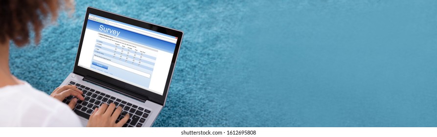 Close-up Of Woman Filling Survey Form On Digital Tablet Against Blue Background