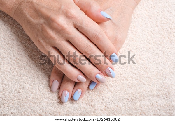 Close-Up Of Woman Fingers With\
Nail Art. Woman Hand With Beige and Blue Nail Polish. Selective\
focus