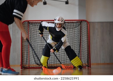 Close-up of woman floorball goalkeeper in helmet concetrating on game in gym. - Powered by Shutterstock