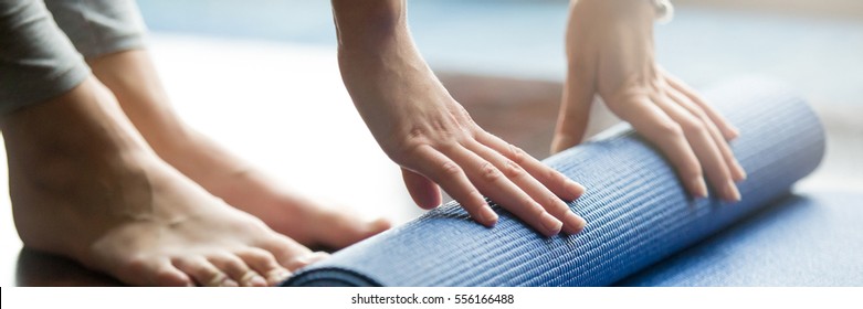 Close-up Of Woman Folding Blue Yoga Or Fitness Mat After Working Out At Home In Living Room. Healthy Life, Keep Fit Concepts. Horizontal Shot. Horizontal Photo Banner For Website Header Design