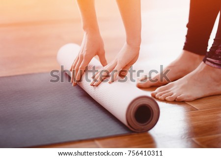 Close-up woman folding roll fitness or yoga mat after working out home in living room. Concept healthy life. 