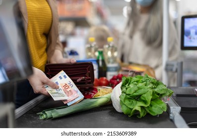Close-up of woman giving money at the cash desk in supermarket - Shutterstock ID 2153609389