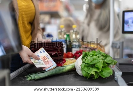 Close-up of woman giving money at the cash desk in supermarket