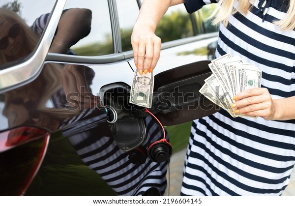 close-up of woman hand with\
cash at the car, put money to car tank, the concept of rising fuel\
prices