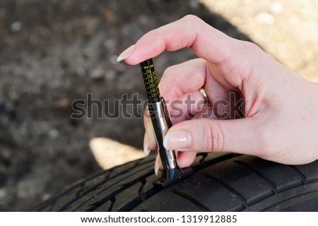 Close-up of woman hand during checking the tread depth of a car tyre with gauge. Hamburg, Germany