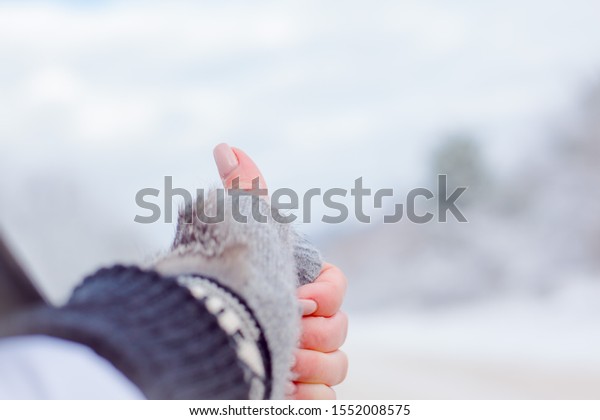 Close-up of woman hand with finger up against the\
beautiful vie of snow\
forest.
