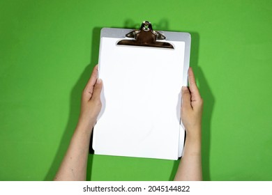 closeup woman hand holding a classic metal clipboard with blank white paper isolated