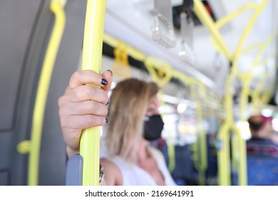 Close-up of woman hand holding handrail in tram or bus. Female in facial mask. Coronavirus restrictions in public transport