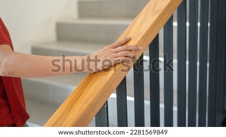 Close-up at woman hand is holding on the stairway handrail during walking up the stair. People in action photo, selective focus.