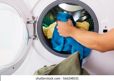 Close-up Of Woman Hand Loading Dirty Clothes In Washing Machine