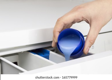 Closeup Of A Woman  Hand Pouring Liquid Detergent In The Washing Machine