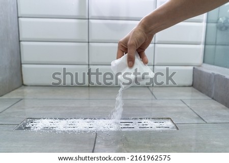 Closeup of woman hand pouring pipe cleaner granules. Removal of blockage in the shower of a special remedy with powder. Clean the blockages in the bathroom with chemicals.