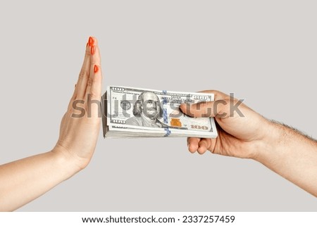 Closeup of woman hand refusing money, man hand offering dollar banknotes, corruption. showing Indoor studio shot isolated on gray background.