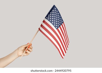 Closeup of woman hand showing american flag, traveling to United States, immigration. Indoor studio shot isolated on gray background. - Powered by Shutterstock