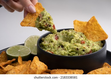 Closeup of woman hand with tortilla chip or nachos with tasty guacamole dip - Powered by Shutterstock