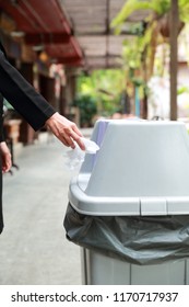 Closeup Woman Hand Tossing Piece Of Paper In Trash
