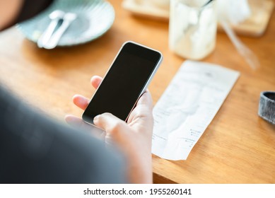 Closeup Woman Hand Use The Smart Phone After Meal In The Coffee Shop, With Bill Of Food And Drink On The Table, Scan Or Online Payment, Bill Calculating Concept