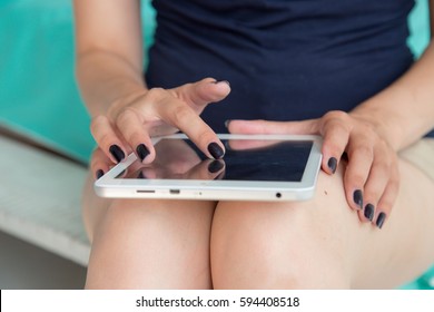 Close-up Woman Hands With Black Nails Using Digital Tablet Computer Ipad Touchscreen.