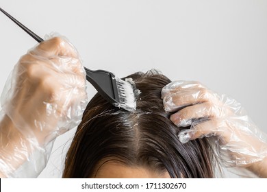 Closeup woman hands dyeing hair using a black brush. Colouring of white hair at home.