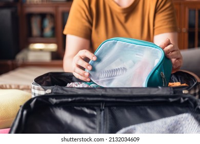 Closeup Woman Hands Holding Mesh Cosmetic Bag And Try To Put Them In Luggage. Packing To Go On A Getaway Vacation.