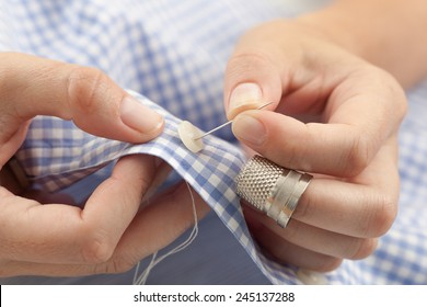 Closeup Of Woman Hands Sewing A Button.