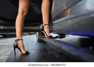 Close-up of woman in high heels stepping out of car, elegance and style on display with wet surface. - Powered by Shutterstock